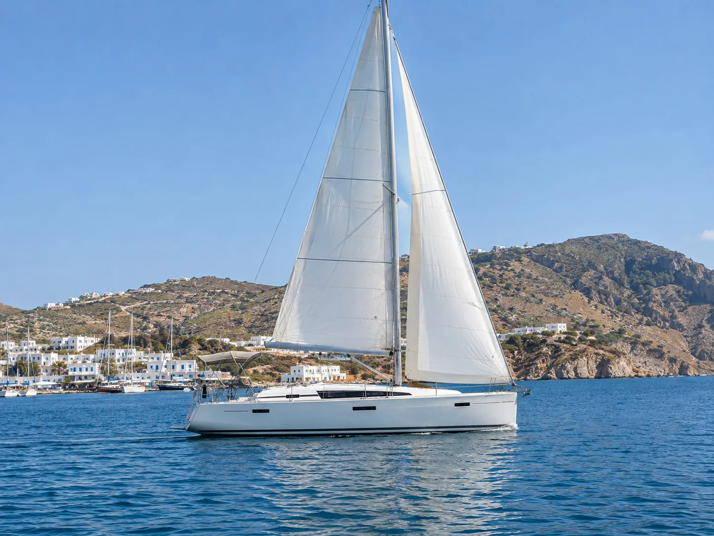 Weiße Segelyacht unter Segeln vor einer griechischen Insel